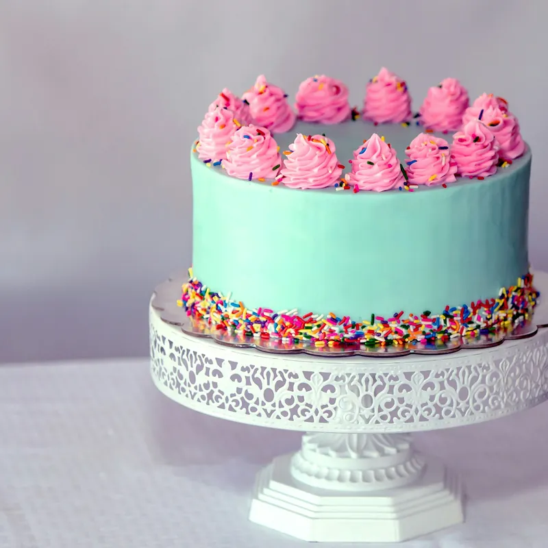 A mint-green celebration cake topped with pink buttercream swirls