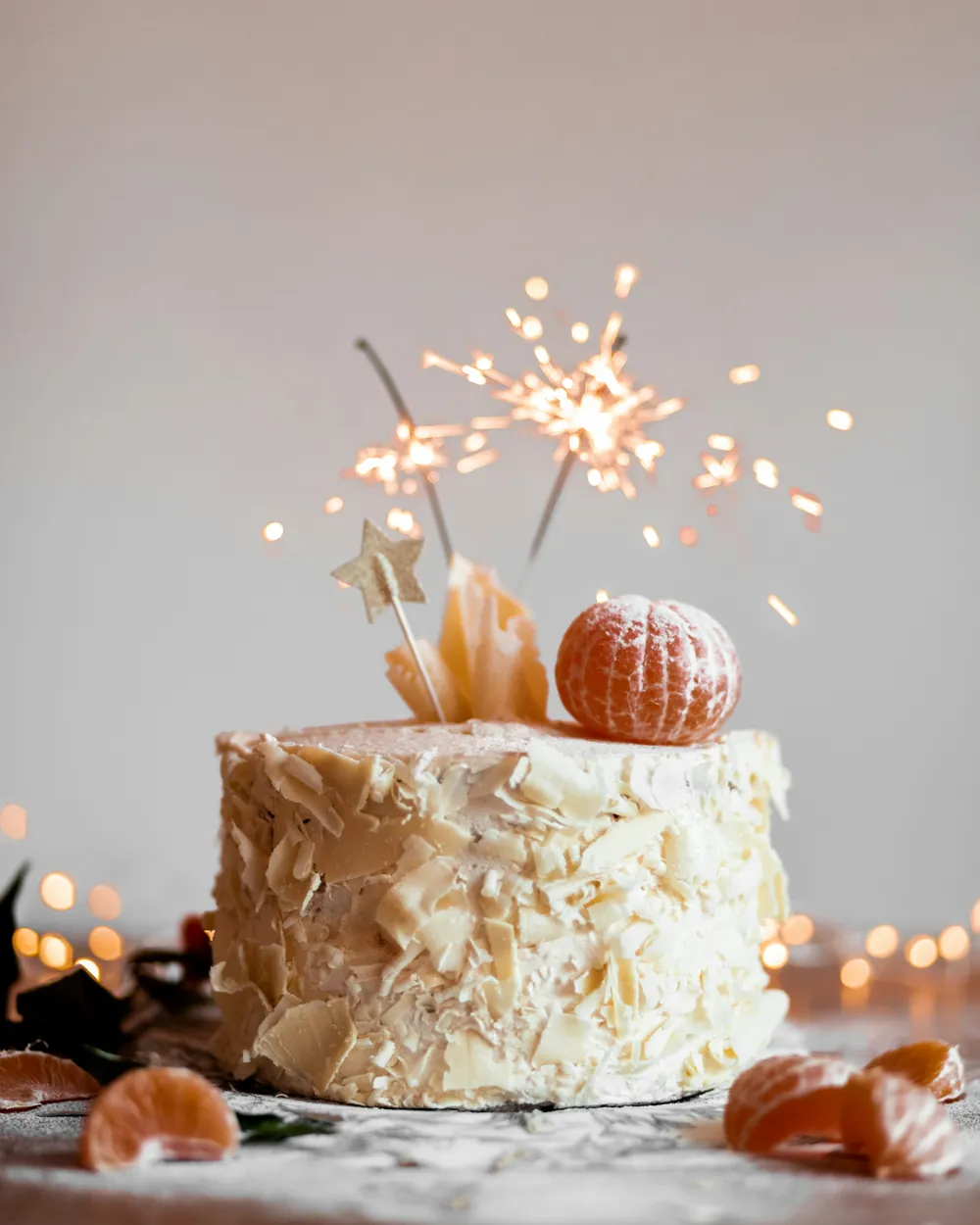 A layered celebration cake topped with a lit sparkler