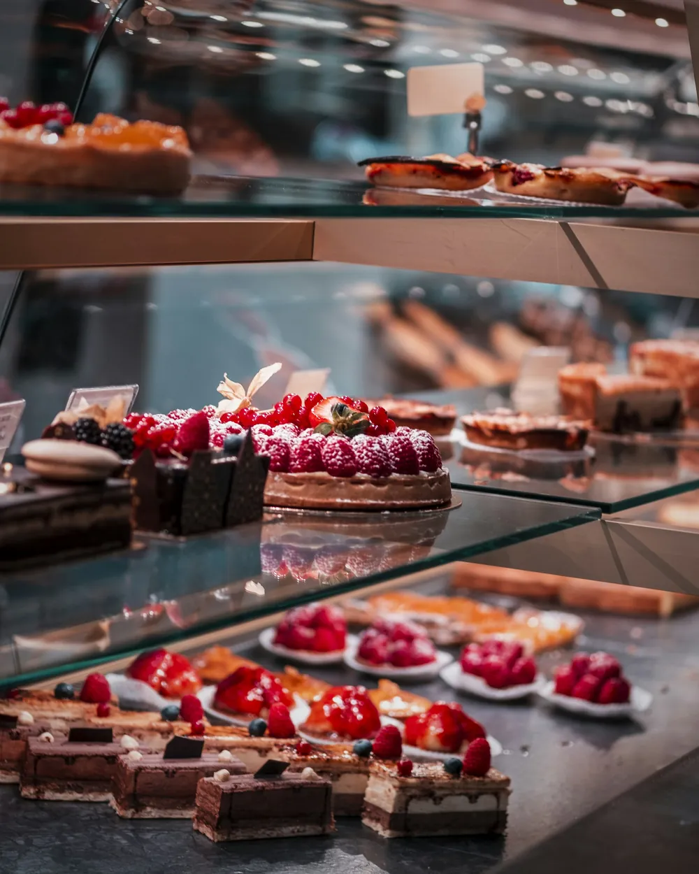 A bakery display case of fruit tarts and small cakes