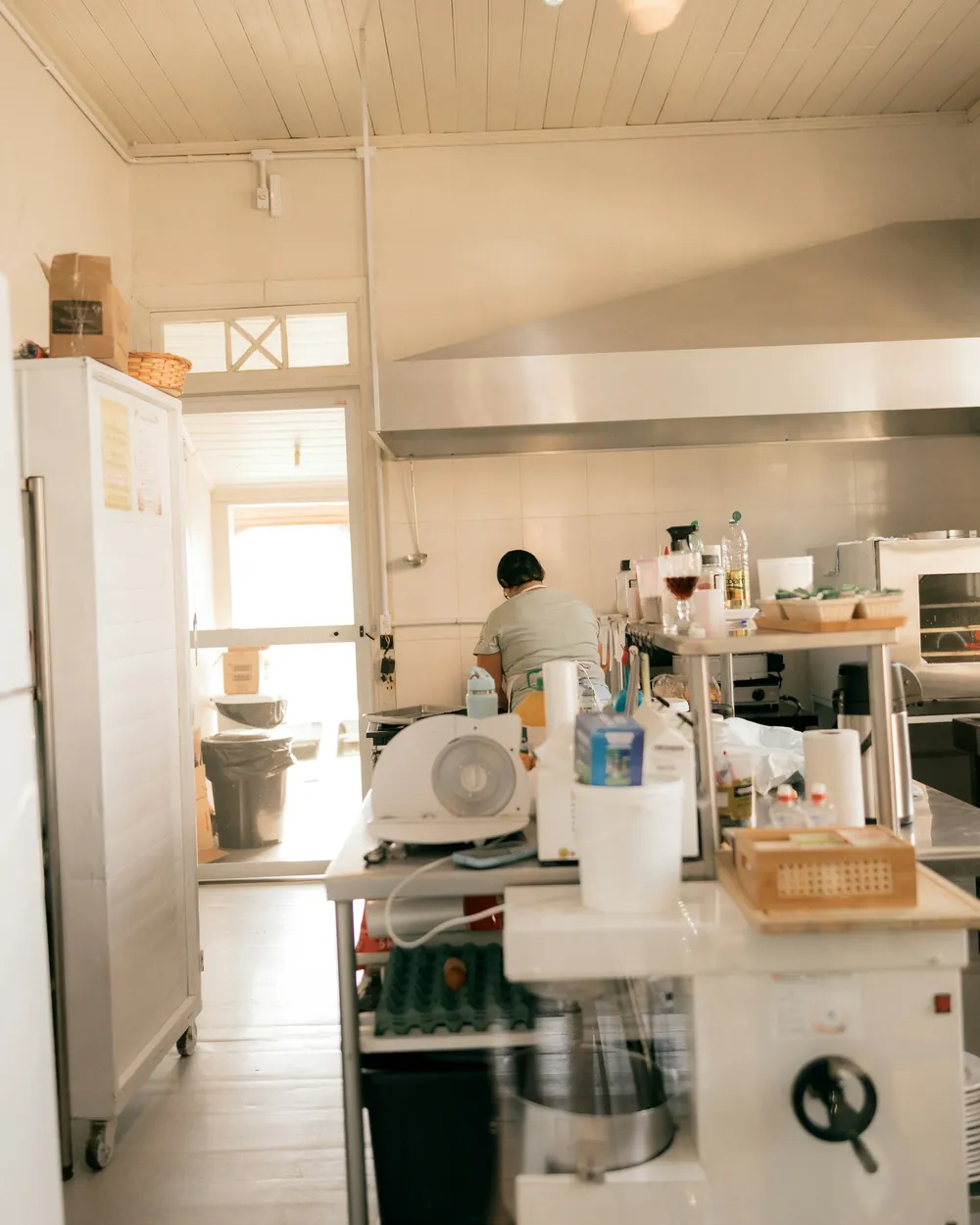 A bright commercial bakery kitchen with a baker at work