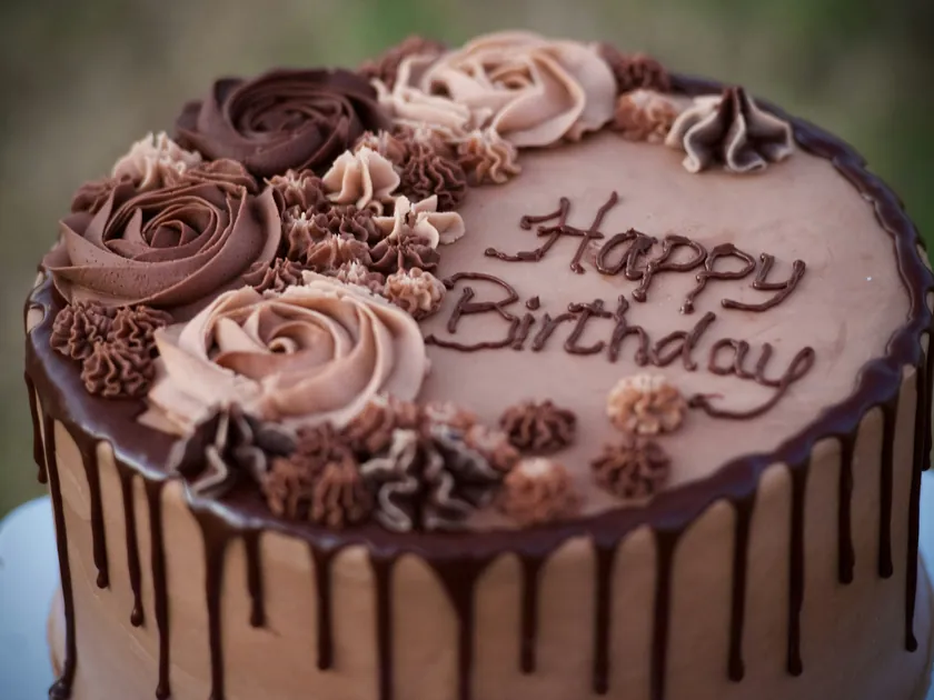A chocolate Happy Birthday cake decorated with piped buttercream roses