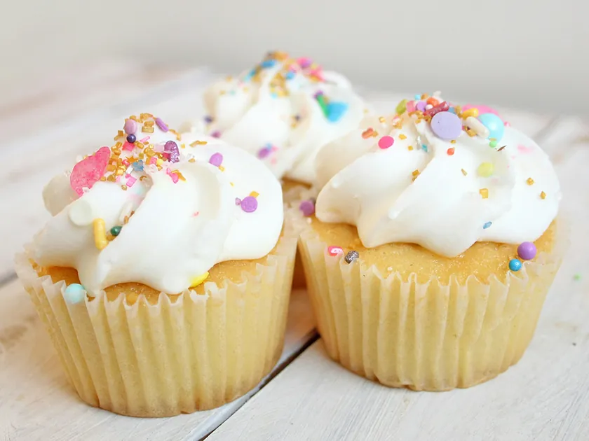 Two vanilla cupcakes with swirled white frosting and sprinkles