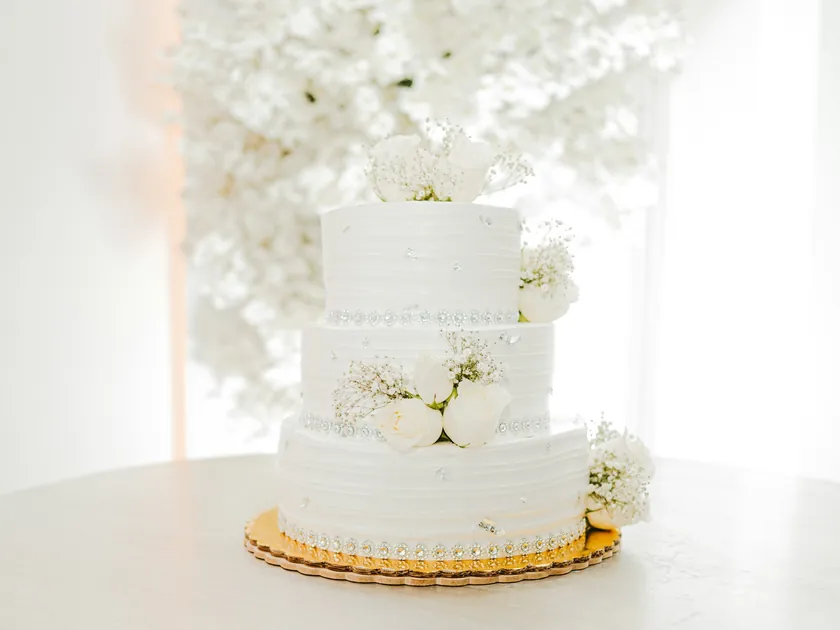 A three-tier white wedding cake finished with fresh white flowers