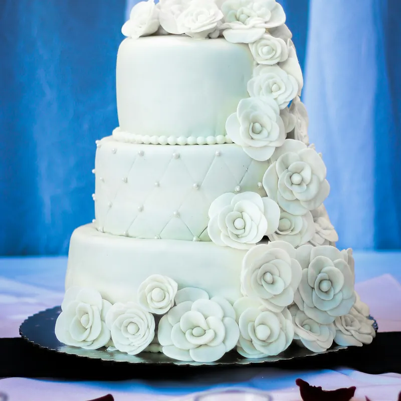 A tiered wedding cake cascading with white sugar roses