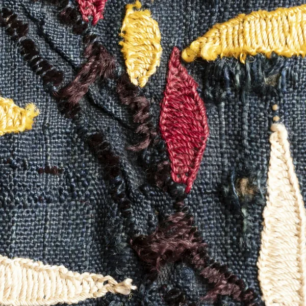 Close-up of embroidered shapes on dark woven fabric