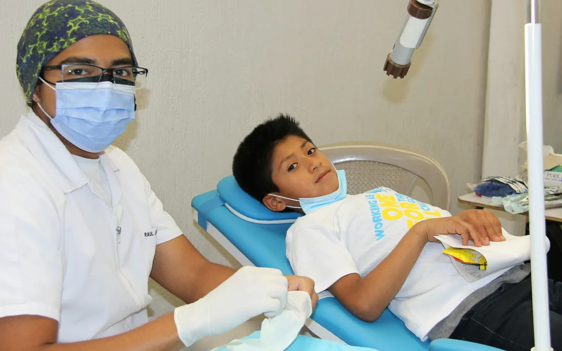 A boy relaxing in the dental chair beside a friendly clinician