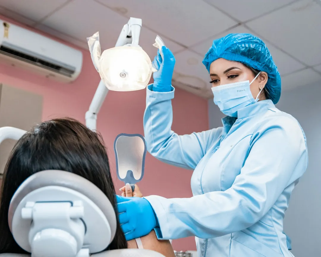 A hygienist adjusting the overhead light before a patient's cleaning